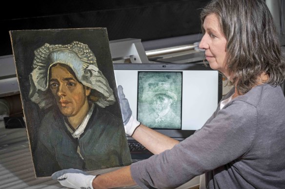 Conservator Lesley Stevenson holds Head of a Peasant Woman alongside an X-ray image of the hidden Van Gogh self-portrait beneath it. 