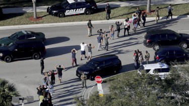 Students hold their hands in the air as they are evacuated by police from Marjory Stoneman Douglas High School in Parkland, Florida after shooting. 