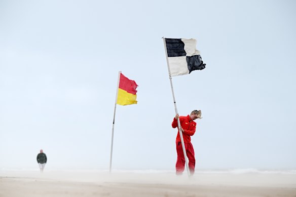 n RNLI lifeguard battles against the strong winds on Portsteward Strand as she plants a warning flag advising swimmers against entering the water in Portstewart, United Kingdom. 