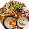 Breakfast board loaded with fried eggs, ful medames, zaatar manoush, labneh, cold-cuts, assorted pickles, fresh vegies and village cheeses.