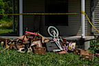 Police tape and debris are seen at a home where authorities say they removed 16 children and arrested four adults.