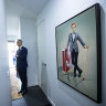 Auctioneer Jarrod Couch stands by a portrait of Rhys Nicholson before the auction.