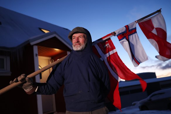 Jens Kjeldsen, 70, who is holding a staff adorned with the flags of the three territories of the Kingdom of Denmark: Denmark, Greenland and the Faroe Islands, holds an hour-long vigil outside the U.S. consulate on January 20, 2026 in Nuuk, Greenland. European leaders are scheduled to meet later this week to formulate their response to U.S. President Donald Trump’s recent threat of punitive tariffs against countries who obstruct his desire to acquire Greenland. 