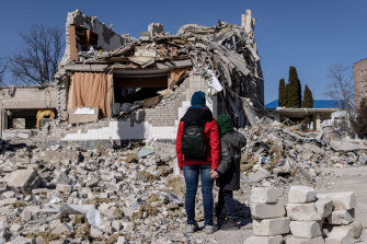 People look at the remains of a school hit by Russian missiles in Zhytomyr, Ukraine, 