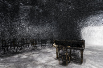 Chiharu Shiota’s installation In Silence (burnt piano, burnt chairs) at the GOMA Gallery.