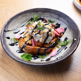 The prawn and blue swimmer crab cake with confit kipfler, pickled watermelon radish and squid ink.