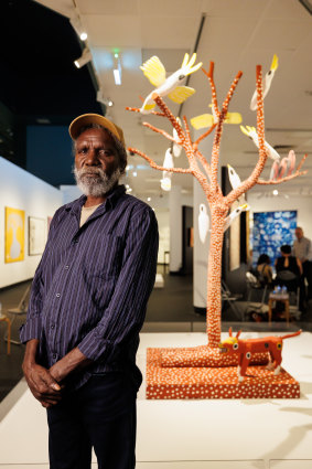 Keith Wikmunea with his work Ku’, Theewith & Kalampang: The White Cockatoo, Galah and the Wandering Dog.