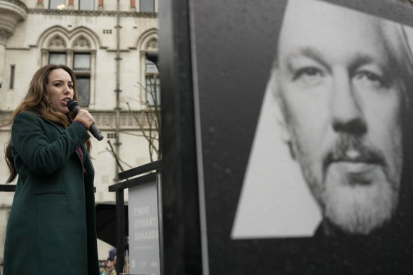 Stella Assange, wife of Julian Assange, speaks besides a poster of Julian Assange at the Royal Courts of Justice in February.