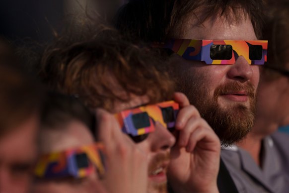People observe the partial eclipse with special protective glasses in Liverpool, England.