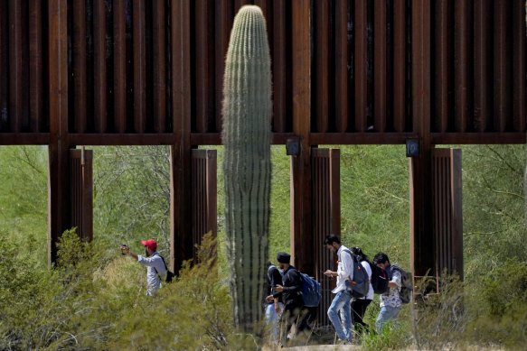 A group of people claiming to be from India walk past open border wall storm gates after crossing through the border fence in the Tucson sector of the  US-Mexico border in Organ Pipe Cactus National Monument near Lukeville, Arizona, in late August.