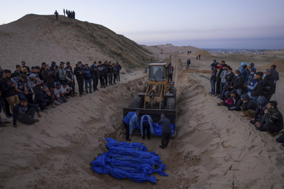 A bulldozer unloads the bodies of Palestinians killed in Israeli strikes and turned over by the Israeli military during a mass funeral in Rafah.
