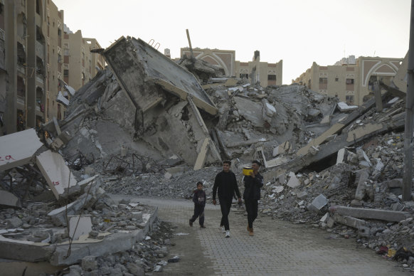 Young Palestinians walk amid rubble of destroyed buildings at a neighbourhood in Khan Younis, Gaza Strip, in early December.