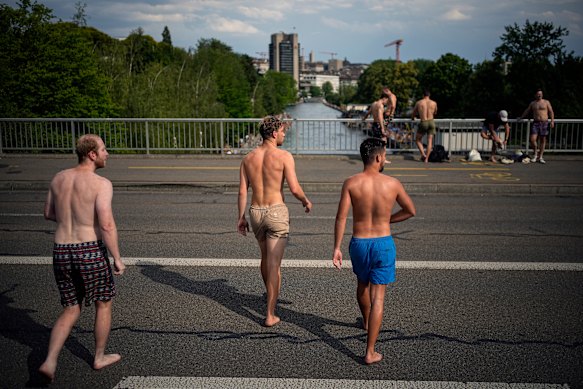 Persone attraversano un ponte prima di tuffarsi nel fiume Limmat a Zurigo, in Svizzera.