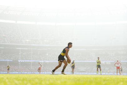 Richmond’s Liam Baker preparing to kick the ball as smoke haze hung around the MCG on Easter Sunday.