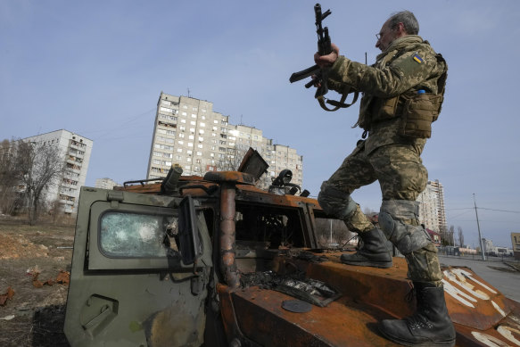 A Ukrainian soldier stands on a destroyed Russian APC in Kharkiv.