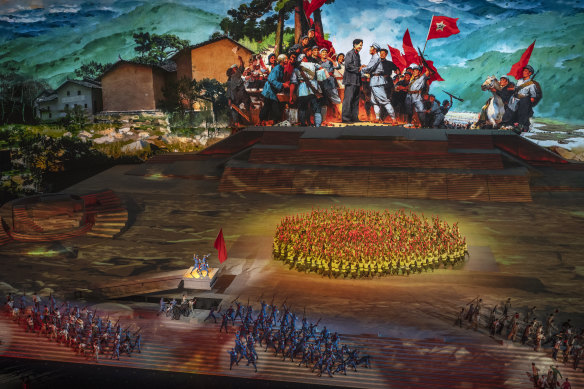 Performers take part in a historical routine in front of screen showing a painting of the late Chairman Mao Zedong. 