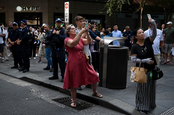 Bystanders stop to film the procession.