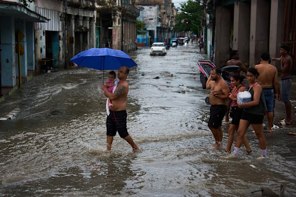 A man protects a girl from the rain with an umbrella in Havana, Cuba, Wednesday, Sept. 23, 2026.
