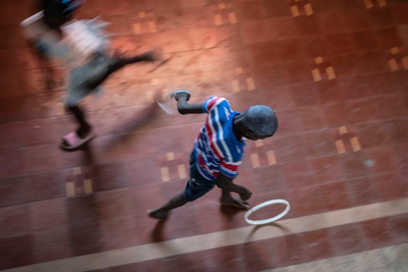 A youth rolls a hoop in the National Theater where families displaced by gang violence are taking shelter in Port-au-Prince, Haiti.
