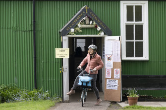 A woman leaves a polling station on a bike at Kings Road in Pontcanna in Cardiff, Wales.