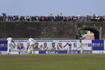 Steve Smith bats while protesters converge atop the Dutch fort behind Galle stadium.