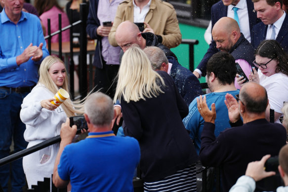 A woman throwing a drink over Reform UK leader Nigel Farage as he launches his election candidacy.