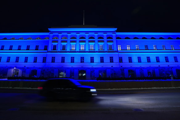 A car passes the Ministry of Foreign Affairs building illuminated in blue, in Helsinki. 