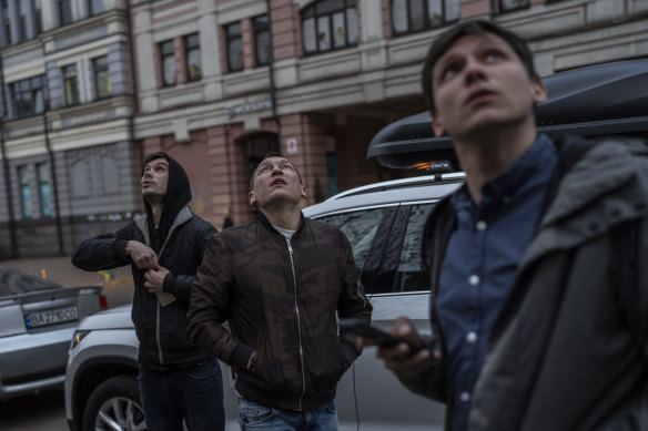 Pedestrians watch Kiev's air defenses attempt to shoot down a drone in Kiev.