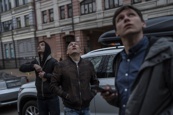 Pedestrians observe Kyiv’s air defence systems trying to down a drone in Kyiv on Thursday. Ukraine’s capital was the target of an air attack for the third time in four days.