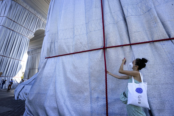 A visitor holds one of the red ropes holding the fabric in place.