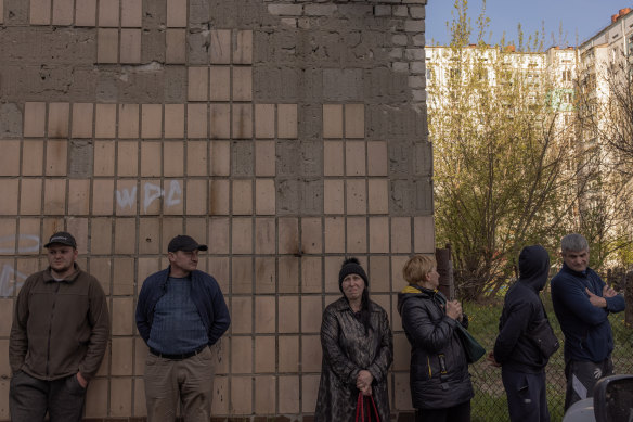 People gather at the site of the destroyed building that was hit during the Russian attack on April 28.