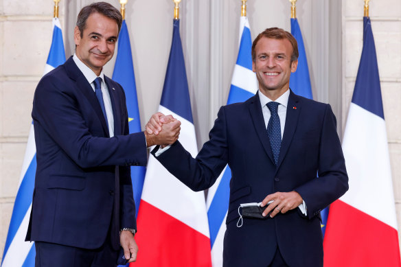 Greek Prime Minister Kyriakos Mitsotakis, left, and French President Emmanuel Macron shake hands after the signing of a new defence deal.