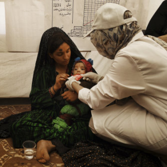 A medical staff member shows Gul Zada  how to feedher son ready-to-use food.