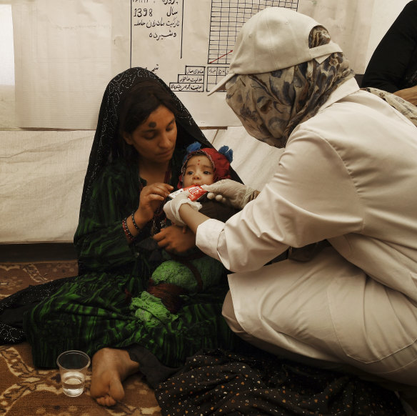 A medical staff member shows Gul Zada  how to feed her son ready-to-use food.