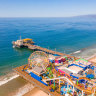 Aerial view of Santa Monica Pier and its amusement park, ferris wheel and roller coaster.