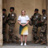 Australian gymnast Emily Whitehead poses for a photographer as armed security personnel walk by in Paris.