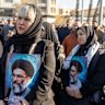 Women hold posters as thousands of people gather in Enghelab Square, Tehran, after Iranian state media confirmed the death of Ayatollah Ali Khamenei.
