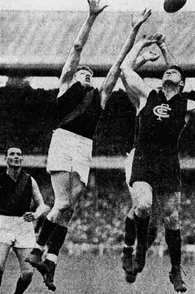 McClure, of Essendon, stretches full length to mark in front of Bennett, of Carlton. Cassin, of Essendon, stood down to await developments.