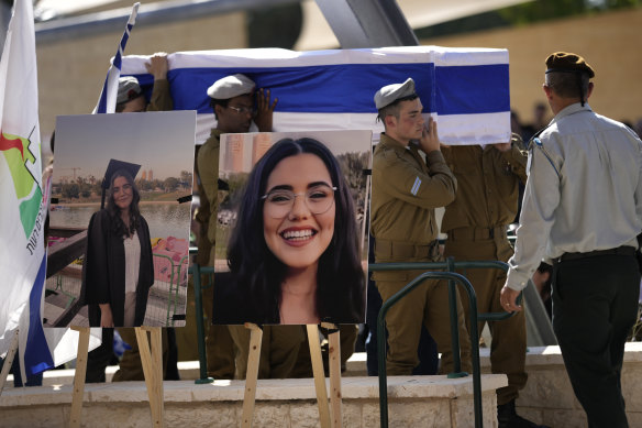 Soldiers carry the coffin of Noa Marciano, a soldier in the Israel Defence Forces, as they walk near photos of her displayed at her funeral at a cemetery in Israel. 