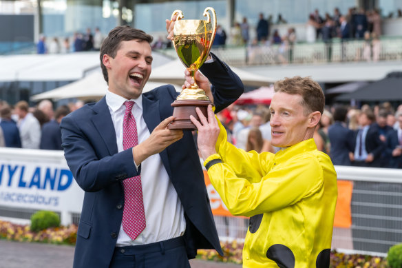 Co-trainer Sam Freedman and jockey Mark Zahra hold aloft the Caulfield Cup after Without A Fight’s win on Saturday.