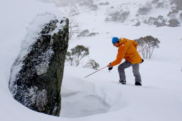 As the blizzard sets in, Peter Cocker uses an avalanche probe to check the best spot to dig a snow cave.