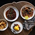 A spread of crab blini with hollandaise, chips, steak Diane and Skull Island prawns with black pepper butter (clockwise from left).