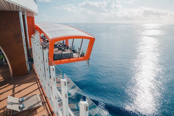 Passengers enjoy drinks over the ocean on Celebrity Edge’s “Magic Carpet”, which glides up and down the ship’s exterior.