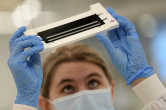 Research assistant Emily checks a COVID flow cell before putting it into the sequencer at the Wellcome Sanger Institute, Genome Campus, Hinxton, England.