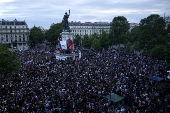 People stand in Republique Plaza  in Paris as they react to the projection of results during the second round of the legislative elections.