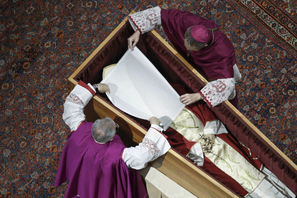 Bishops Georg Gaenswein, right, and Diego Ravelli cover the face of Pope Emeritus Benedict XVI with a white silk veil.