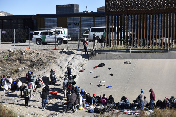 Migrants wait to cross the US-Mexico border from Ciudad Juárez, Mexico, next to US Border Patrol vehicles in El Paso, Texas on Wednesday, December 14.