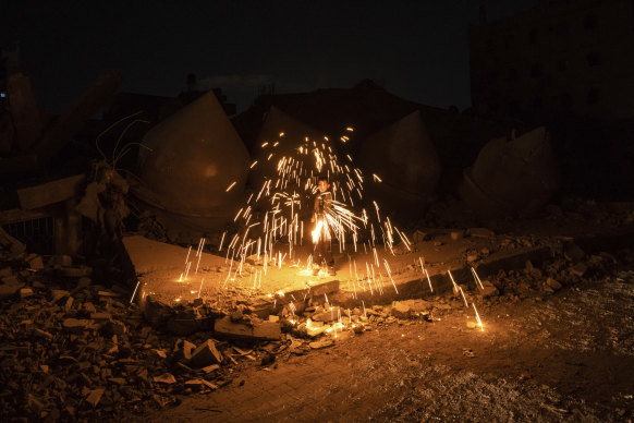 A Palestinian boy plays with fireworks as he celebrates the start of the Muslim holy month of Ramadan next to a mosque destroyed by the Israeli airstrikes in Rafah, Gaza Strip.