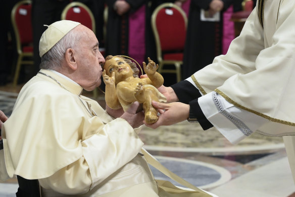 Pope Francis kisses a statue of Baby Jesus as he presides over Christmas Eve Mass in St Peter’s Basilica at the Vatican on Saturday.