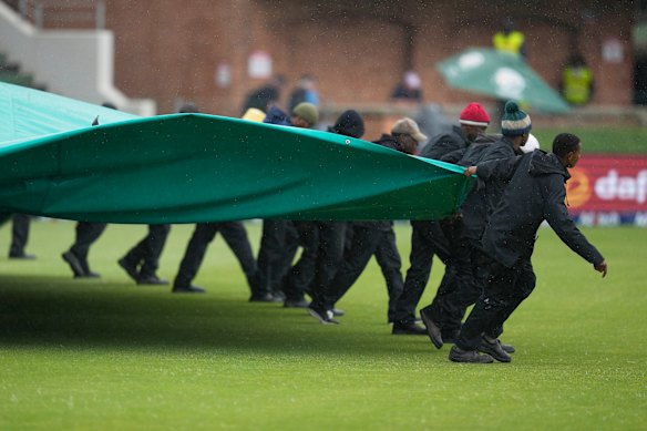 Groundsmen pull covers over the field as rain interrupts play on day five of the second Test between South Africa and Australia.